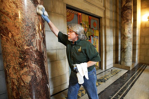 Perry Shuman wipes down columns at the State Capitol in Lincoln, Neb., Monday, March 23, 2020. Nebraska lawmakers are reconvening on Monday to pass emergency funding for the coronavirus outbreak. (AP Photo/Nati Harnik)