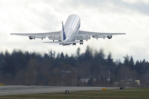 A Boeing Dreamlifter airplane, used to carry large parts for airplane assembly, takes off from Paine Field near Boeing's manufacturing facility in Everett, Wash., Monday, March 23, 2020, north of Seattle. Boeing announced Monday that it will be suspending operations and production at its Seattle area facilities due to the spread of the new coronavirus. (AP Photo/Ted S. Warren)