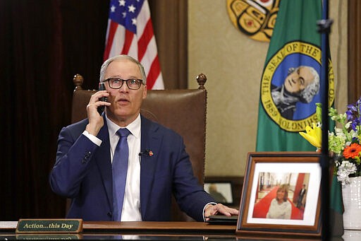 Gov. Jay Inslee takes a phone call just before speaking about additional plans to slow the spread of coronavirus before a televised address from his office Monday, March 23, 2020, in Olympia, Wash. Inslee has ordered non-essential businesses to close and the state&#146;s more than 7 million residents to stay home unless necessary in order to slow the spread of COVID-19. (AP Photo/Elaine Thompson)