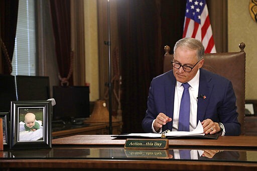 Washington Gov. Jay Inslee prepares to speak about additional plans to slow the spread of coronavirus before a televised address from his office Monday, March 23, 2020, in Olympia, Wash. The latest update from the Washington state Department of Health showed there have been at least 110 coronavirus deaths in the state and more than 2,200 confirmed cases. (AP Photo/Elaine Thompson)