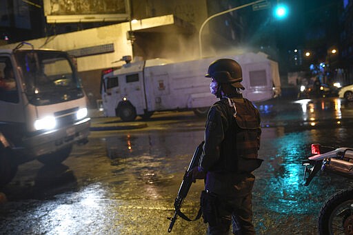 Bolivarian National Guards use a water cannon to spray disinfectant as a preventive measure against the spread of the new coronavirus, in Caracas, Venezuela, Saturday, March 21, 2020. (AP Photo/Matias Delacroix)