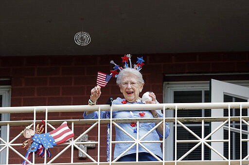 A resident of the Lambeth House, where a cluster of the coronavirus has formed, reacts from her balcony as opera singers Irini Hymel and Bryan Hymel sing to the quarantined residents in New Orleans, Friday, March 20, 2020. The home has 23 known cases of the coronavirus as of late Wednesday. At least five of about 260 residents have died from the virus within a week. (AP Photo/Gerald Herbert)