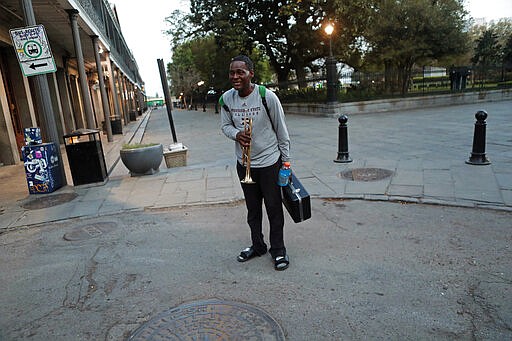 A street musician asks to play music for money in the nearly deserted French Quarter in New Orleans, Sunday, March 22, 2020. With much of the city already hunkered down due to the coronavirus pandemic, Louisiana Gov. John Bel Edwards issues a shelter-in-place order to take effect starting Monday at 5:00 PM. (AP Photo/Gerald Herbert)