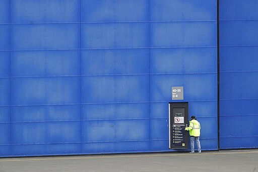 A worker opens a door at Boeing's manufacturing facility in Everett, Wash., Monday, March 23, 2020, north of Seattle. Boeing announced Monday that it will be suspending operations and production at its Seattle area facilities due to the spread of the new coronavirus. (AP Photo/Ted S. Warren)