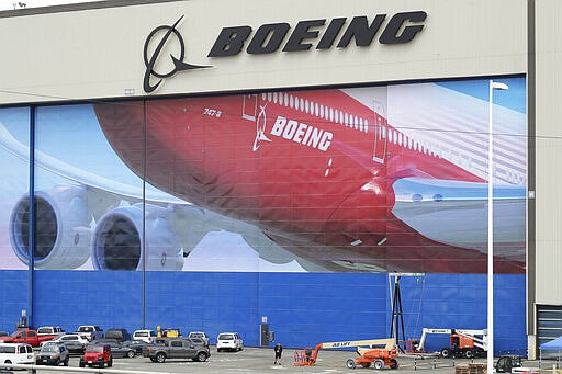 A worker walks near a mural of a Boeing 747-8 airplane at the company's manufacturing facility in Everett, Wash., Monday, March 23, 2020, north of Seattle. Boeing announced Monday that it will be suspending operations and production at its Seattle area facilities due to the spread of the new coronavirus. (AP Photo/Ted S. Warren)