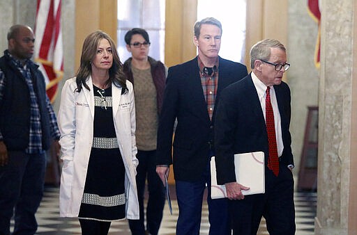 Ohio Department of Health director Dr. Amy Acton, second from left, Ohio Lt. Gov. Jon Husted, center, and Gov. Mike DeWine walk into a coronavirus news conference, Sunday, March 22, 2020 at the Ohio Statehouse in Columbus, Ohio. Gov. Mike DeWine's administration is enacting a stay-at-home order as the number of cases in the state spiked. DeWine said the stay-at-home order will start to be enforced Tuesday by local health departments and local law enforcement. (Doral Chenoweth/The Columbus Dispatch via AP)