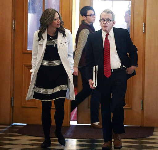 Ohio Department of Health director Dr. Amy Acton, left, and Gov. Mike DeWine walk into a coronavirus news conference Sunday, March 22, 2020 at the Ohio Statehouse in Columbus, Ohio. Gov. Mike DeWine's administration is enacting a stay-at-home order as the number of cases in the state spiked. DeWine said the stay-at-home order will start to be enforced Tuesday by local health departments and local law enforcement. (Doral Chenoweth/The Columbus Dispatch via AP)