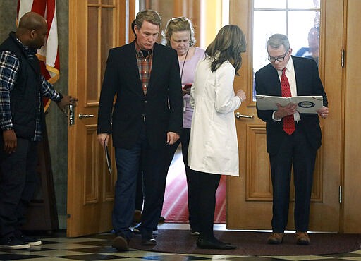 Ohio Lt. Gov. Jon Husted, communications director Lisa Peterson, Ohio Department of Health director Dr. Amy Acton, and Gov. Mike DeWine walk into a coronavirus news conference Sunday, March 22, 2020 at the Ohio Statehouse in Columbus, Ohio. Gov. Mike DeWine's administration is enacting a stay-at-home order as the number of cases in the state spiked. DeWine said the stay-at-home order will start to be enforced Tuesday by local health departments and local law enforcement. (Doral Chenoweth/The Columbus Dispatch via AP)