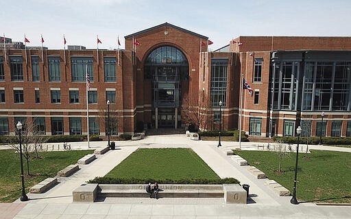 A couple relaxes in front of the Ohio Union at the Ohio State University Sunday, March 22, 2020 in Columbus, Ohio. Due to coronavirus, all in-person, face-to-face teaching has been suspended at the Ohio State University. Photographed March 22, 2020. (Doral Chenoweth/The Columbus Dispatch via AP)