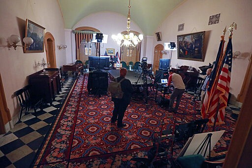 Members of Ohio Gov. Mike DeWine's communications team prepare the State Room for the daily coronavirus news conference Sunday, March 22, 2020 at the Ohio Statehouse in Columbus, Ohio. Gov. Mike DeWine's administration is enacting a stay-at-home order as the number of cases in the state spiked. DeWine said the stay-at-home order will start to be enforced Tuesday by local health departments and local law enforcement. (Doral Chenoweth/The Columbus Dispatch via AP)