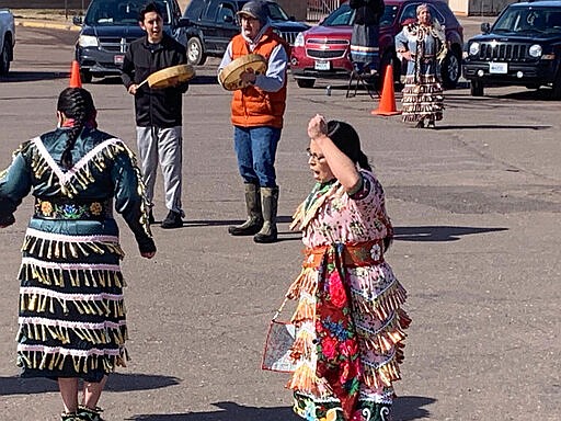 This Saturday, March 21, 2020, photo provided by Lynn Maday Bigboy shows singers and dancers at a social-distancing powwow outside the Bad River Casino in Ashland, Wis. People across Indian Country are organizing online and social-distancing powwows and posting videos of healing dances to offer support during the coronavirus pandemic. (Lynn Maday Bigboy via AP)