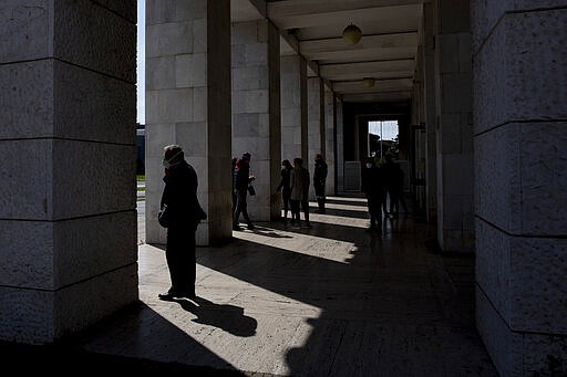 People line up outside a bank in the EUR neighborhood in Rome, Monday, March 23, 2020. Italian Premier Giuseppe Conte has told the nation he is tightening the lockdown to fight the rampaging spread of coronavirus, shutting down all production facilities except those that are &quot;necessary, crucial, indispensable to guarantee&quot; the good of the country. For most people, the new coronavirus causes only mild or moderate symptoms. For some it can cause more severe illness, especially in older adults and people with existing health problems. (AP Photo/Alessandra Tarantino)