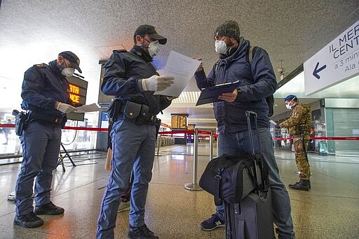 Police officers check passenger's travel documents, at Rome's Termini main train station, Monday, March 23, 2020. For most people, the new coronavirus causes only mild or moderate symptoms. For some it can cause more severe illness, especially in older adults and people with existing health problems.(AP Photo/Andrew Medichini)