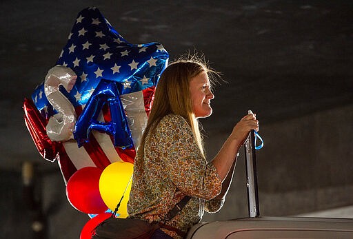 In this Sunday, March 22, 2020 photo, Gina Hardy from Beaver, Utah, looks for her son Elder Ethan Hardy, as he returns from his mission to the Philippines, at the Salt Lake City International Airport.  Sen. Mitt Romney and Utah state leaders are criticizing a large gathering of family and friends who went to the Salt Lake City airport to welcome home missionaries when people are supposed to be keeping their distance from one another to prevent more spread of the coronavirus. (Rick Egan/The Salt Lake Tribune via AP)