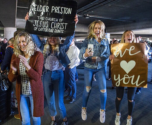 In this Sunday, March 22, 2020 photo, the Preston family cheer as they see Elder Kaleb Preston as he returns from his mission in the Philippines, at the Salt Lake City International Airport. Sen. Mitt Romney and Utah state leaders are criticizing a large gathering of family and friends who went to the Salt Lake City airport to welcome home missionaries when people are supposed to be keeping their distance from one another to prevent more spread of the coronavirus. (Rick Egan/The Salt Lake Tribune via AP)