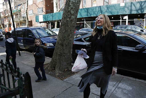 In this March 19, 2020 photo, Freida Rothman talks to a Holocaust survivor before dropping a meal off on her doorstep in Brooklyn, New York. Volunteers like Rothman are helping ensure Holocaust survivors isolated in their homes because of coronavirus concerns have access to food. (AP Photo/Jessie Wardarski)