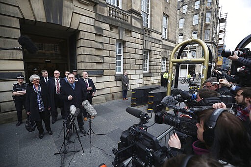 Alex Salmond foreground left, speaks to the media as he leaves the High Court after he was cleared of attempted rape and a series of sexual assaults, including one with intent to rape, against nine women, who were all either working for the Scottish Government or within the SNP at the time, in Edinburgh, Monday March 23, 2020. (Jane Barlow/PA via AP)