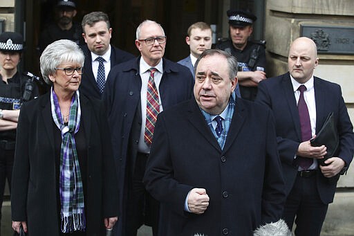 Alex Salmond foreground speaks to the media as he leaves the High Court after he was cleared of attempted rape and a series of sexual assaults, including one with intent to rape, against nine women, who were all either working for the Scottish Government or within the SNP at the time, in Edinburgh, Monday March 23, 2020. (Jane Barlow/PA via AP)