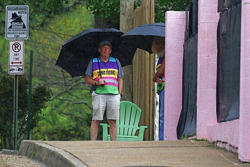 Jackson Women's Health Organization clinic escorts brave an early afternoon rain as they look for abortion opponents that protest daily at Mississippi's only state licensed abortion facility, Monday, March 23, 2020. A number of governors are moving to ban most abortions in their respective states during the coronavirus outbreak, declaring they don't qualify as essential surgeries. Diane Derzis, owner of the abortion clinic in Mississippi, told The Associated Press that the clinic had not been told by the state to stop providing the procedure. (AP Photo/Rogelio V. Solis)