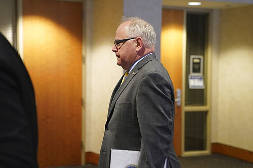 Minnesota Gov. Tim Walz walks into a news conference in St. Paul, Minn., Monday, March 16, 2020. Walz ordered bars and restaurants across Minnesota to temporarily close to customers who dine in amid fears of coronavirus cases. (Glen Stubbe/Star Tribune via AP)