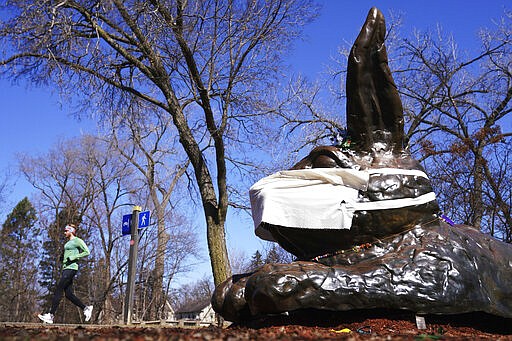 A jogger passes by the Minnehaha Bunny, who someone jokingly added a protective mask during the coronavirus pandemic, Friday, March 2020 in South Minneapolis. (Anthony Souffle/Star Tribune via AP)