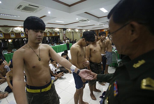 In this Friday, April 1, 2016 photo, a Thai soldier checks the physical health of a Thai man during a military conscription in Bangkok, Thailand. The human rights group Amnesty International says many new conscripts in Thailand's military are physically, sexually and mentally abused, with some cases amounting to torture.  (AP Photo)