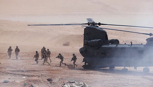 Emirati troops disembark an Emirati Boeing CH-47 Chinook during a military exercise at an Emirati military base home to a Military Operations in Urban Terrain facility in al-Hamra, United Arab Emirates, Monday, March 23, 2020. The U.S. military held the major exercise Monday with Emirati troops in the UAE's far western desert at a facility designed to look like a Mideast city amid ongoing tensions with Iran. (AP Photo/Jon Gambrell)