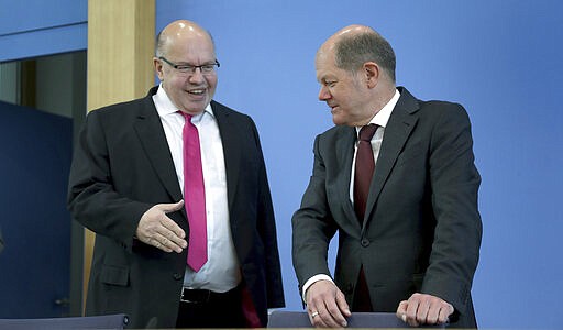 German Economy Minister, Peter Altmaier, left, tries to shake hands with German Finance Minister Olaf Scholz, right, prior to a press conference in Berlin, Germany, Monday, March 23, 2020 on the supplemental budget 2020 and how the ministries will react against the new coronavirus. For most people, the new coronavirus causes only mild or moderate symptoms. For some it can cause more severe illness (AP Photo/Michael Sohn, pool)