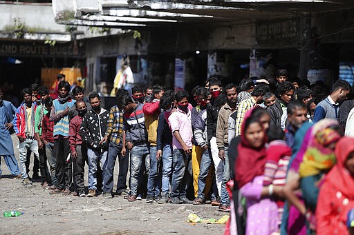 Indian passengers who got stranded at a bus terminal line up for free food being distributed by shop keepers during a day long lockdown amid growing concerns of coronavirus in Jammu, India, Sunday, March 22, 2020. India is observing a 14-hour &#147;people's curfew&#148; called by Prime Minister Narendra Modi in order to stem the rising coronavirus caseload in the country of 1.3 billion. India's government has made fervent appeals to the public to practice social distancing, but experts say, the same is nearly impossible in many Indian cities that are among the world's most densely populated areas. For most people, the new coronavirus causes only mild or moderate symptoms. For some it can cause more severe illness. (AP Photo/Channi Anand)