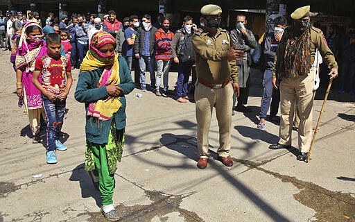 Indian passengers who got stranded at a bus terminal line up for free food being distributed by shop keepers during a day long lockdown amid growing concerns of coronavirus in Jammu, India, Sunday, March 22, 2020. India is observing a 14-hour &#147;people's curfew&#148; called by Prime Minister Narendra Modi in order to stem the rising coronavirus caseload in the country of 1.3 billion. For most people, the new coronavirus causes only mild or moderate symptoms. For some it can cause more severe illness. (AP Photo/Channi Anand)