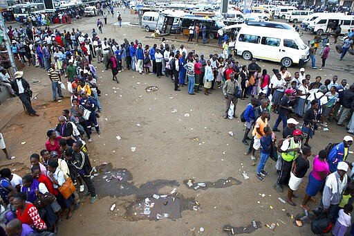 People queue for public transport in Harare, Zimbabwe, Monday, March, 23, 2020. Zimbabwe has closed its borders to non essential human traffic following its first recorded coronavirus related death. (AP Photo/Tsvangirayi Mukwazhi)