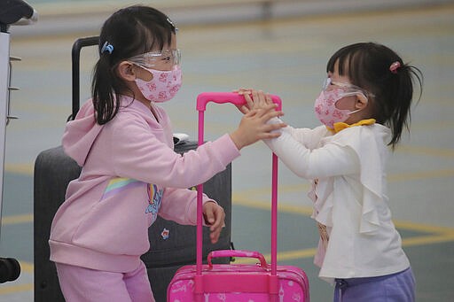 Young passengers wear face masks to protect against the coronavirus as they arrive at the Hong Kong airport, Monday, March 23, 2020. For most, the coronavirus causes only mild or moderate symptoms, such as fever and cough. But for a few, especially older adults and people with existing health problems, it can cause more severe illnesses, including pneumonia. (AP Photo/Kin Cheung)