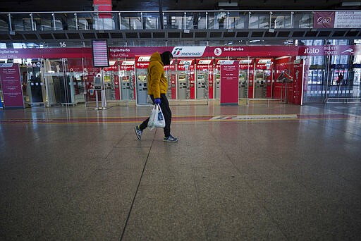 A person walks past ticket machines in an almost empty Termini main train station, in Rome, Monday, March 23, 2020. For most people, the new coronavirus causes only mild or moderate symptoms. For some it can cause more severe illness, especially in older adults and people with existing health problems.(AP Photo/Andrew Medichini)