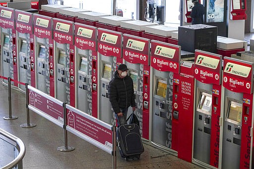 A person walks past ticket machines in an almost empty Termini main train station, in Rome, Monday, March 23, 2020. For most people, the new coronavirus causes only mild or moderate symptoms. For some it can cause more severe illness, especially in older adults and people with existing health problems.(AP Photo/Andrew Medichini)