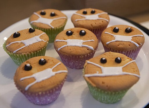 Timed to the current outbreak of the worldwide coronavirus, Covid-Free Cupcakes with icing masks are on display in the Cheesecake House and Restaurant in Bangkok, Thailand, Monday, March 23, 2020. The cupcakes cost just under a U.S. dollar.  (AP Photo/Sakchai Lalit)