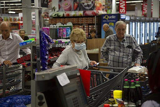 Elderly customers line at the checkout point in a Johannesburg supermarket Wednesday, March 18, 2020, amid panic-buying due to the new coronavirus outbreak. For most people, the new coronavirus causes only mild or moderate symptoms. For some it can cause more severe illness. (AP Photo/Denis Farrell)