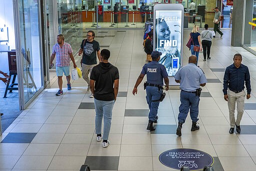 South African police walk through the Rosebank mall in Johannesburg, South Africa, Monday March 23, 2020. South African President Cyril Ramaphosa is to address the nation later in the day to announce the latest measures taken to control the spread of the coronavirus in South Africa. For most people the virus causes only mild or moderate symptoms. For others it can cause more severe illness, especially in older adults and people with existing health problems. (AP Photo/Jerome Delay)