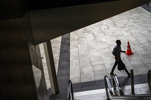 A shopper walks through the Rosebank shopping mall in Johannesburg, South Africa, Monday March 23, 2020. South African President Cyril Ramaphosa is to address the nation later in the day to announce the latest measures taken to control the spread to the coronavirus in South Africa. For most people the virus causes only mild or moderate symptoms. For others it can cause more severe illness, especially in older adults and people with existing health problems. (AP Photo/Jerome Delay)