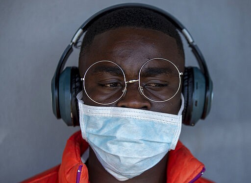 A barber wearing wearing a surgical mask at a hair salon in Soweto, South Africa, Thursday, March 19, 2020. For most people the virus causes only mild or moderate symptoms. For others it can cause more severe illness, especially in older adults and people with existing health problems. (AP Photo/Themba Hadebe)