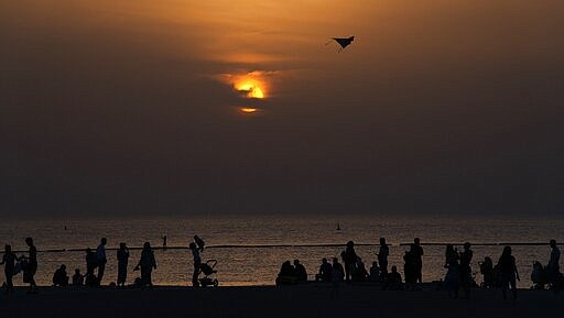 A crowd of more than 10 people gather on a beach despite warnings to maintain a distance from each other over the outbreak of the new coronavirus in Dubai, United Arab Emirates, Friday, March 20, 2020. The United Arab Emirates has closed its borders to foreigners, including those with residency visas, over the coronavirus outbreak, but has yet to shut down public beaches and other locations over the virus. (AP Photo/Jon Gambrell)