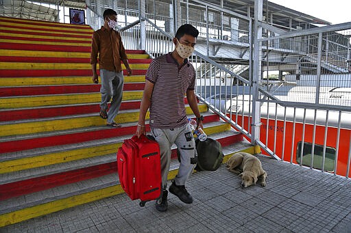 Indian passengers wearing a masks arrive at a railway station in Jammu, India, Monday, March 23, 2020. Authorities have gradually started to shutdown much of the country of 1.3 billion people to contain the outbreak. For most people, the new coronavirus causes only mild or moderate symptoms. For some it can cause more severe illness. (AP Photo/Channi Anand)