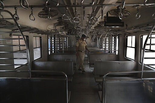 An Indian police officer wearing a mask checks a suburban train before they are locked down in Mumbai, India, Monday, March. 23, 2020. As India expanded its virus-containment measures and halted its lifeblood - the local and national train network, the federal government warned Monday of strict legal action for those who flout the rules. For most people, the new coronavirus causes only mild or moderate symptoms. For some it can cause more severe illness. (AP Photo/Rafiq Maqbool)