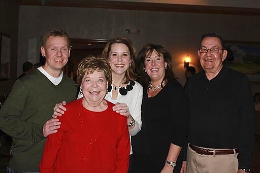 In this 2011 family photo provided by Dawn Bouska, from left, Brad Recka, Patricia Recka, Dawn Bouska, and Amy Malley, pose with Charles Recka, right, for a photo at a banquet in Naperville, Ill. Charles Recka died on March 12, 2020. Deep into the obituary for 87-year-old Recka is the short announcement that &quot;a Mass Celebrating his life will be held at a later date,&quot; a quiet signal popping up in death notices all over the country that the coronavirus that's changed everything about our lives has dramatically changed the way we grieve for the dead, too. (Courtesy of Dawn Bouska via AP)