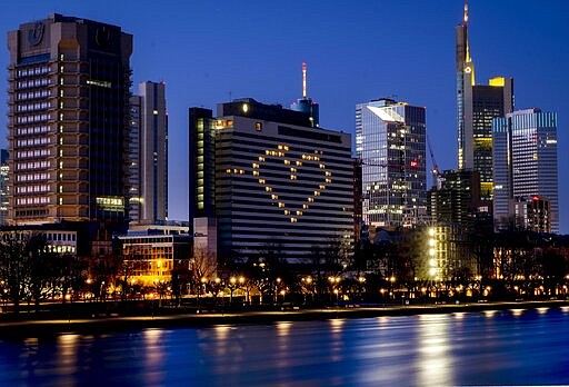 A hotel has switched on the lights in some rooms to form a heart near the buildings of the banking district in Frankfurt, Germany, Sunday, March 22, 2020, as the German government announced new public restrictions to help avoid the spread of Coronavirus.  For some people the COVID-19 coronavirus causes mild or moderate symptoms, but for some it can cause severe illness including pneumonia.(AP Photo/Michael Probst)
