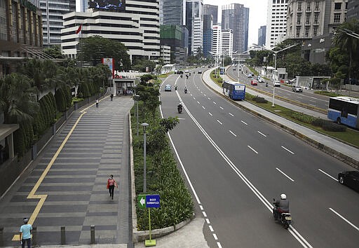 A woman walks on the sidewalk of a section of the normally jammed Sudirman Street in the main business district in Jakarta, Indonesia, Monday, March 23, 2020. Indonesian President Joko Widodo has ruled out the possibility of imposing a lockdown on the capital city and has instead ordered mass testing to contain the coronavirus disease spread and has prepared about 200 hospitals run by government, military and police as well as private as the country braces for an anticipated surge in COVID-19 patients.(AP Photo/Dita Alangkara)