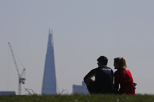 Two people look down from Primrose Hill to view the Shard and central London as a backdrop in London, Monday, March 23, 2020. The British government is encouraging people to practice social distancing to help prohibit the spread of Coronavirus, further restrictions may be imposed if the public do not adhere to their advice. For most people, the new coronavirus causes only mild or moderate symptoms, such as fever and cough. For some, especially older adults and people with existing health problems, it can cause more severe illness, including pneumonia. (AP Photo/Frank Augstein)