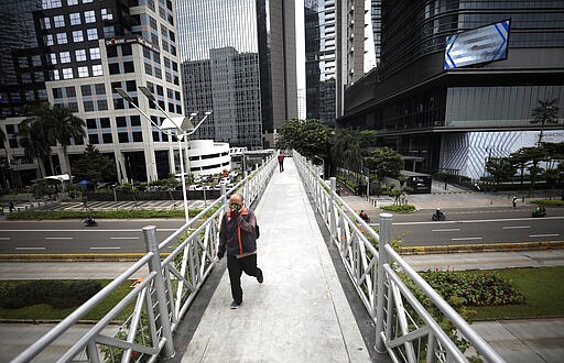 A man wearing a face mask walks over a pedestrian bridge over the normally jammed Sudirman Street in the main business district in Jakarta, Indonesia, Monday, March 23, 2020. Indonesian President Joko Widodo has ruled out the possibility of imposing a lockdown on the capital city and has instead ordered mass testing to contain the coronavirus disease spread and has prepared about 200 hospitals run by government, military and police as well as private as the country braces for an anticipated surge in COVID-19 patients. (AP Photo/Dita Alangkara)