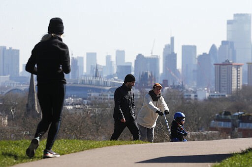 Pedestrians walk on Primrose Hill with the skyline of central London as a backdrop in London, Monday, March 23, 2020. The British government is encouraging people to practice social distancing to help prohibit the spread of Coronavirus, further restrictions may be imposed if the public do not adhere to their advice. For most people, the new coronavirus causes only mild or moderate symptoms, such as fever and cough. For some, especially older adults and people with existing health problems, it can cause more severe illness, including pneumonia. (AP Photo/Frank Augstein)