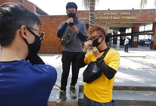 Stranded tourists check flight information at Tribhuvan International airpot in Kathmandu, Nepal, Monday, March 23, 2020.Nepalese government has suspended landing permission to all scheduled international airlines carrying Nepal inbound passengers as a precaution against COVID-19. For most people, the new coronavirus causes only mild or moderate symptoms. For some it can cause more severe illness. (AP Photo/Niranjan Shrestha)