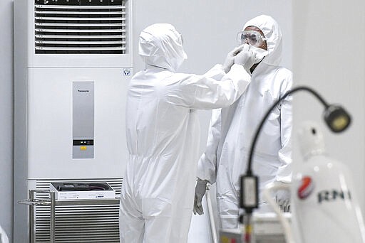 A staff member assists a colleague to don his protective gears at an emergency hospital set up amid the new coronavirus outbreak in Jakarta, Indonesia, Monday, March 23, 2020. Indonesia has changed towers built to house athletes in the 2018 Asian Games to emergency hospitals with a 3,000-bed capacity in the country's hard-hit capital, where new patients have surged in the past week. (Hafidz Mubarak A/Pool Photo via AP)